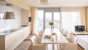 Una habitación de hotel moderna con cocina, comedor y un ventanal con cortinas.