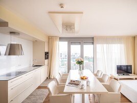 Una habitación de hotel moderna con cocina, comedor y un ventanal con cortinas.