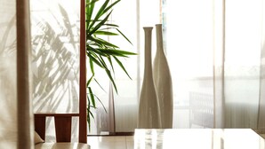 A modern room with a large window, a plant, and two tall vases on a table. - Falkensteiner Residences Senia (Zadar)