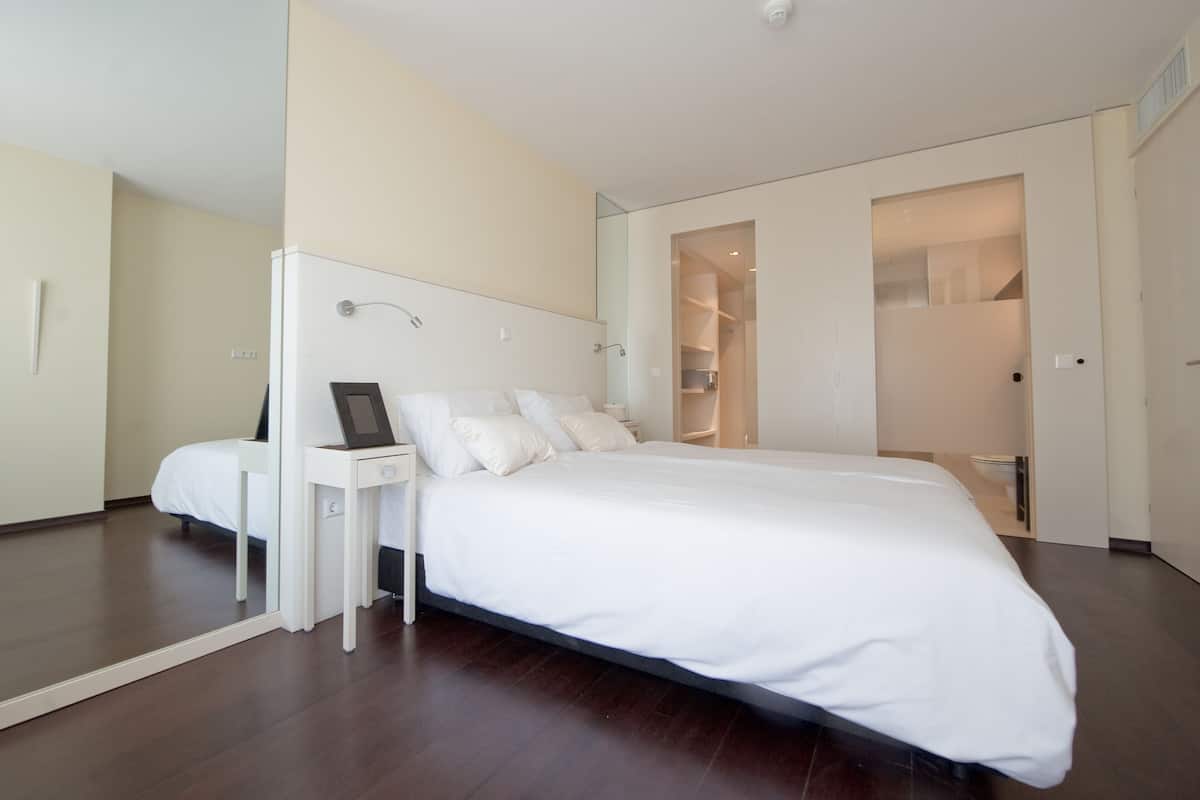 A modern bedroom with a large bed, bedside tables, and a walk-in closet.