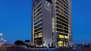 A modern hotel building with a prominent "DOUBLETREE" sign, multiple floors, and a well-lit entrance. - DoubleTree by Hilton Hotel Doha Old Town (Doha)