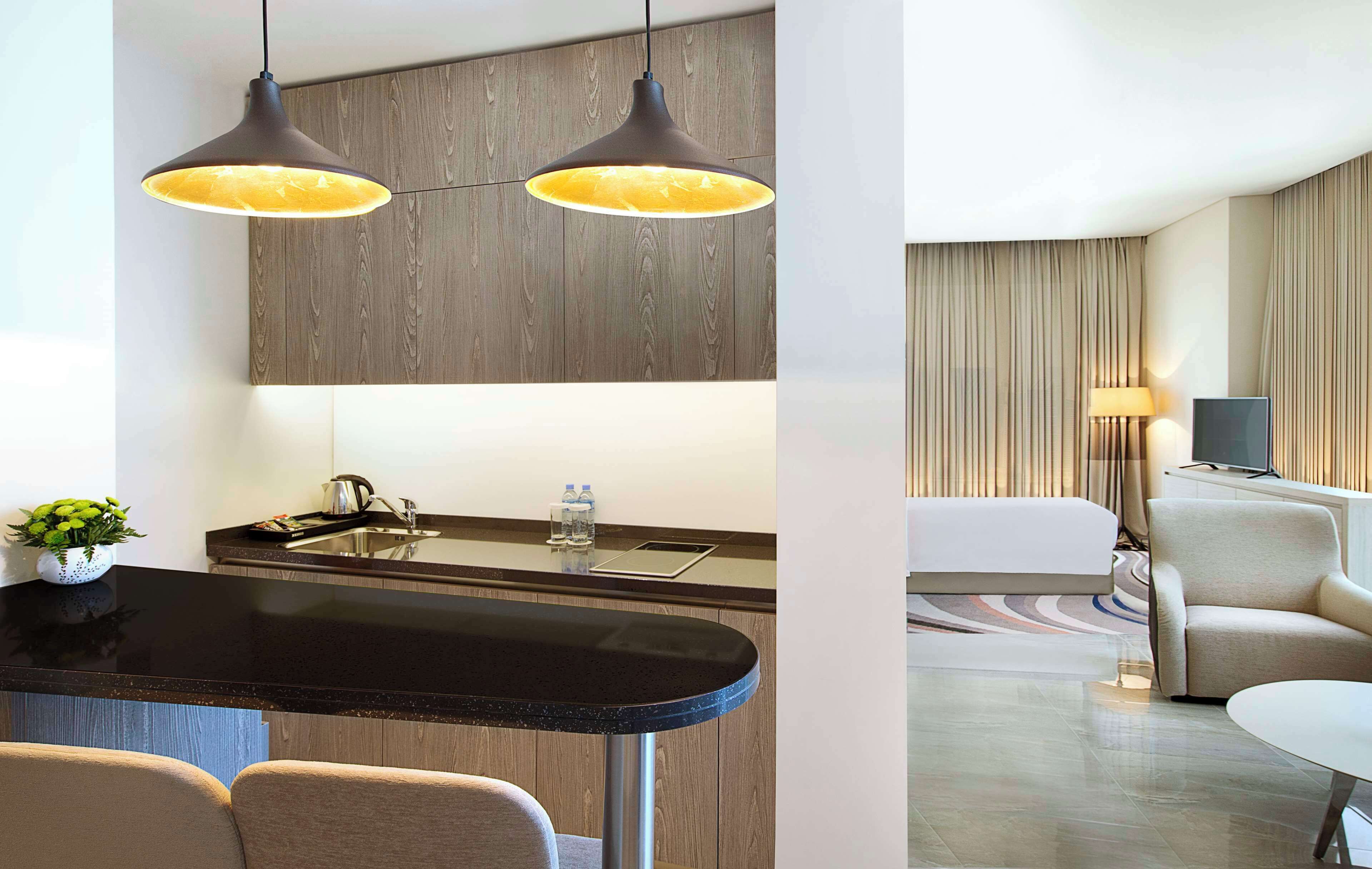A modern kitchen with a black countertop, two pendant lights, and a wooden wall.