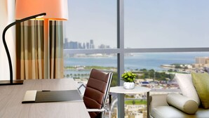 A modern hotel room with a city view, a desk, a leather chair, a small table with a plant, and a sofa. - DoubleTree by Hilton Hotel Doha Old Town (Doha)