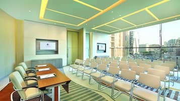A conference room with a long table, multiple chairs, a large window with a city view, and framed certificates on the wall.