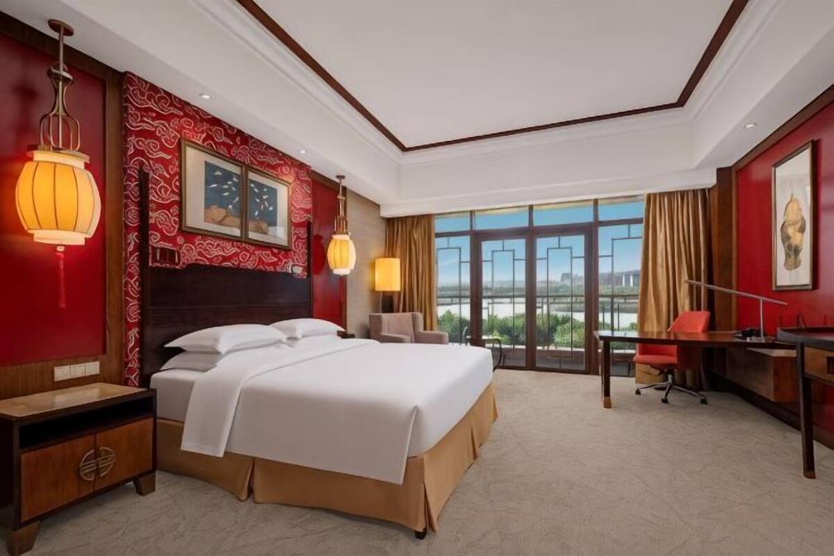 Une chambre d’hôtel avec un grand lit, un bureau et une vue sur la ville.