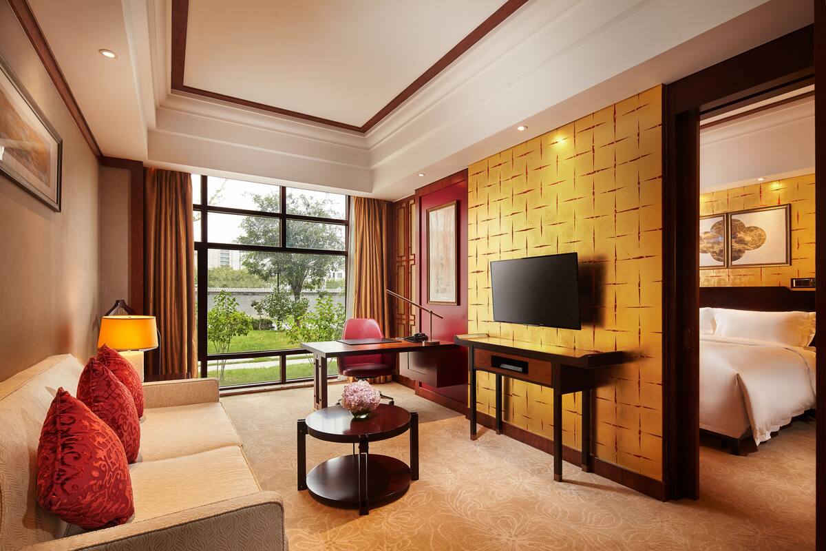 Une chambre d’hôtel avec un canapé, une télévision, un bureau et un lit.