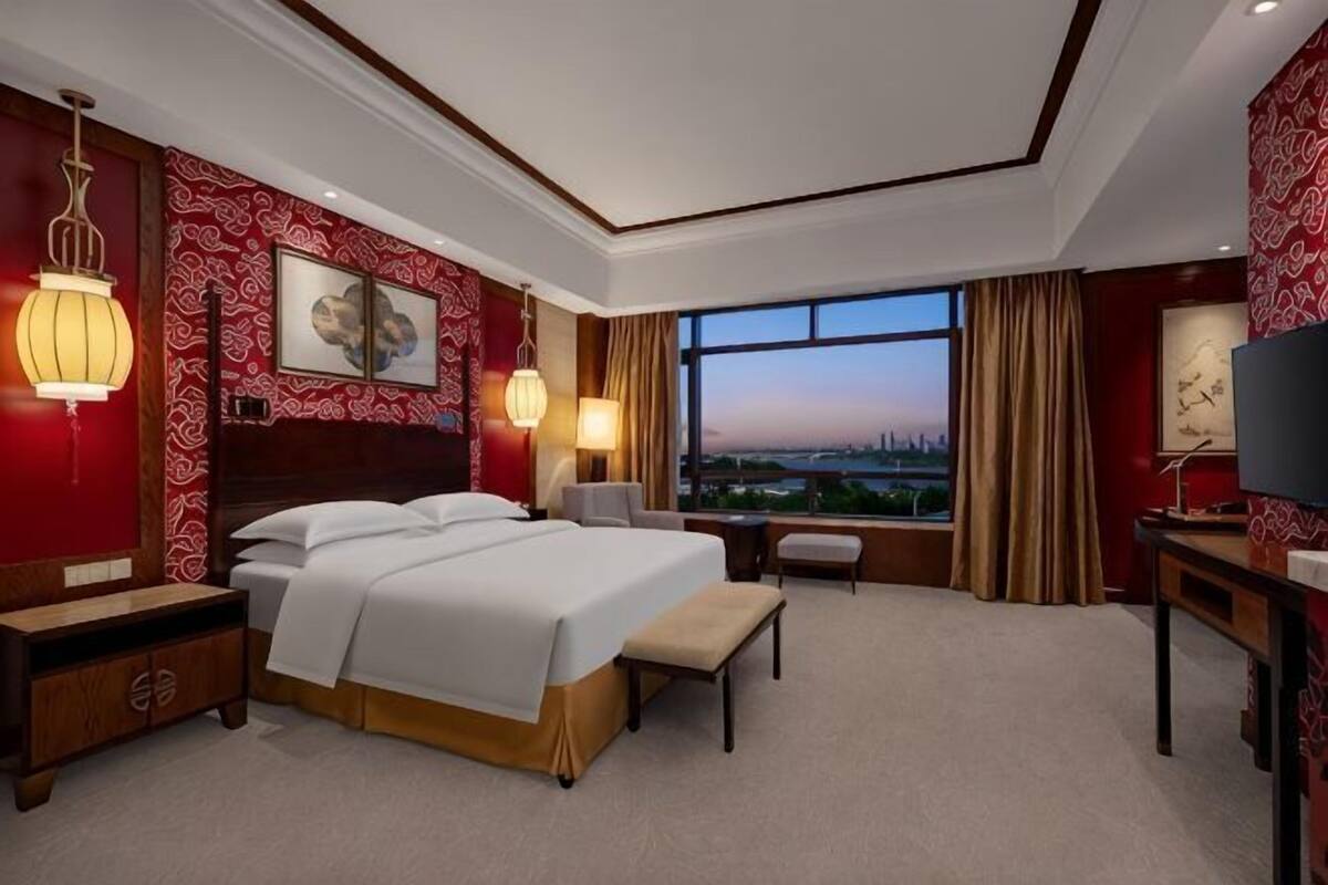 Een hotelkamer met een groot bed, nachtkastjes, een bureau, een stoel en een televisie.