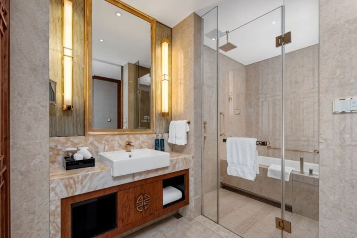 Une salle de bain moderne avec un grand miroir, un lavabo, un meuble-vasque et une douche à parois de verre.