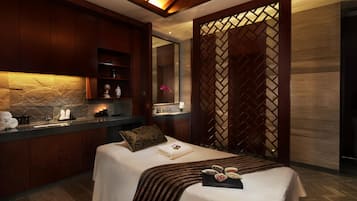 A modern bedroom with a bed, a vanity with a mirror, a sink, and a decorative partition.