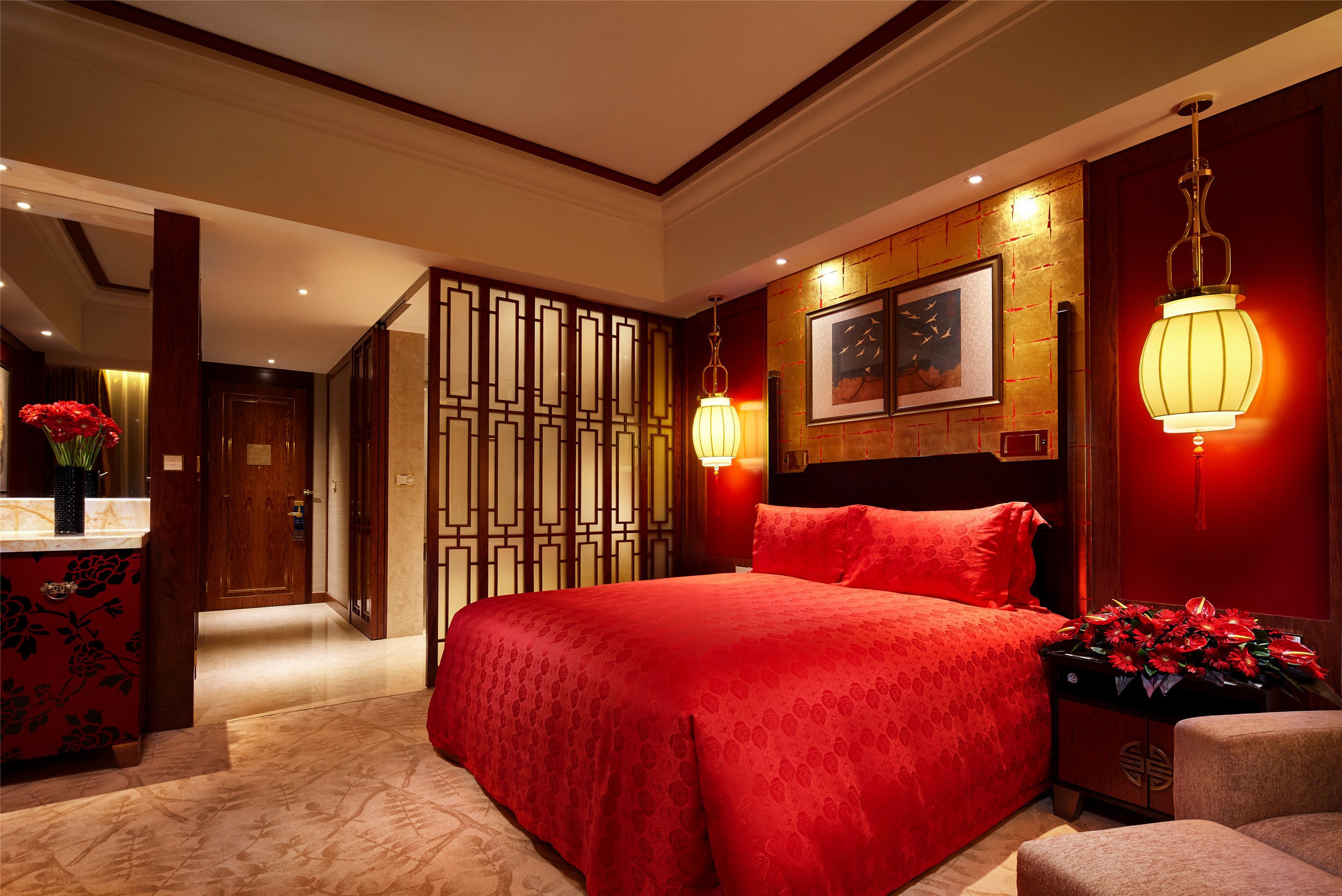 Ein Hotelzimmer mit einem großen Bett, einem Holzkopfteil, einer dekorativen Wandverkleidung, einem gerahmten Bild und einem Nachttisch mit Blumen.