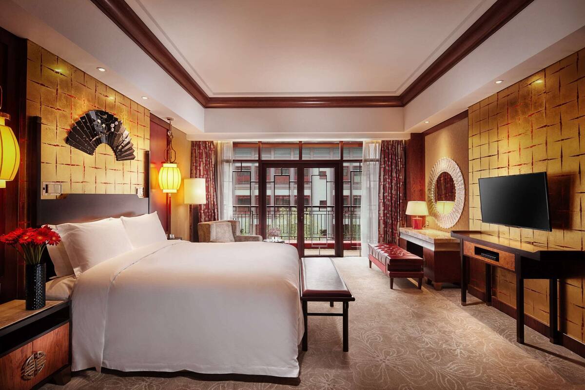 Une chambre d’hôtel avec un grand lit, un bureau, une télévision et un balcon avec vue.