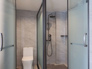 A modern bathroom with a glass-enclosed shower, a toilet, and a glass door. - Baigang International Hotel (Chengdu)
