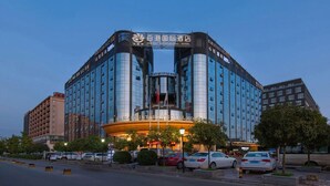A modern hotel with a distinctive curved facade and multiple floors. - Baigang International Hotel (Chengdu)