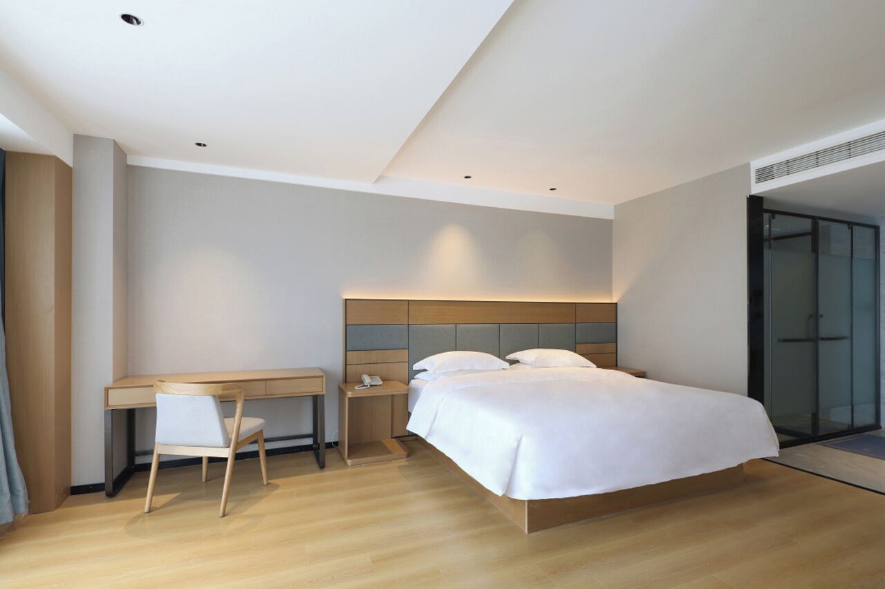 A modern hotel room with a bed, a desk, and a chair.