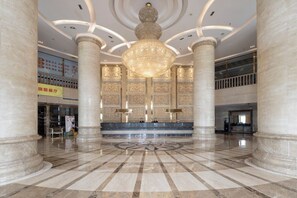 A spacious lobby with marble flooring, large columns, and a grand chandelier. - Baigang International Hotel (Chengdu)