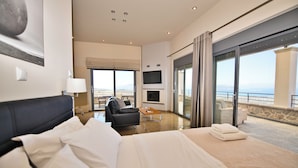 A hotel room with a bed, a sofa, a TV, and a balcony with a view. -  Villa Marini (Aegina)