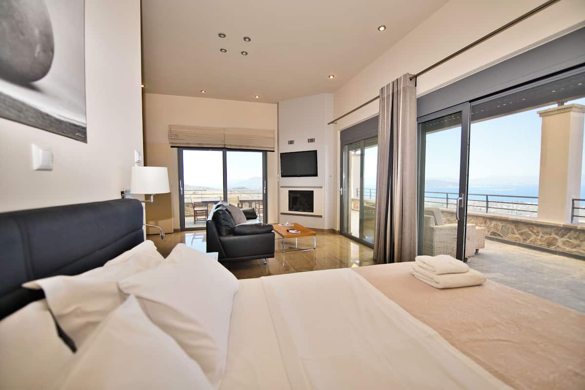Een hotelkamer met een bed, een slaapbank, een televisie en een balkon met uitzicht.