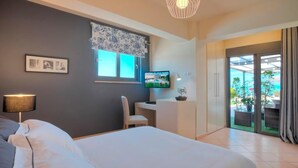 A modern hotel room with a bed, desk, and TV. -  Villa Marini (Aegina)