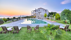A modern villa with a swimming pool, outdoor seating, and lush landscaping. -  Villa Marini (Aegina)