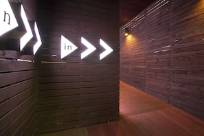A corridor with wooden panel walls and directional arrows indicating the way to the entrance.