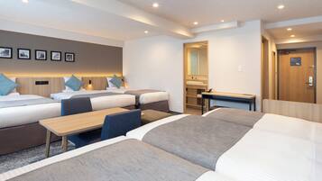 Habitación de hotel con dos camas, un escritorio, un espejo y un baño visible a través de una puerta abierta.