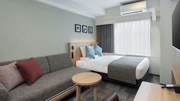 Hotellihuone, jossa on sänky, sohva, pieni pöytä ja televisio.