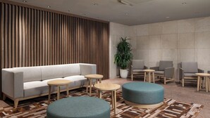 A modern lounge area with a sofa, round tables, and ottomans. - HOTEL MYSTAYS Iidabashi (Tokyo)
