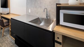 A modern kitchen with a stainless steel sink, a microwave, and a built-in oven. - HOTEL MYSTAYS Iidabashi (Tokyo)