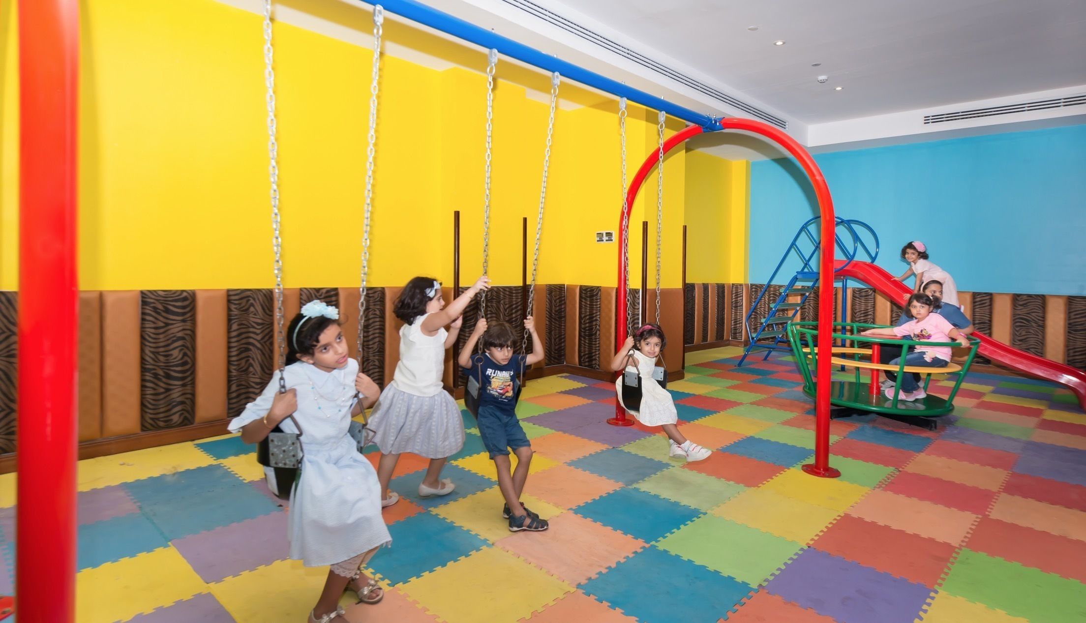 A children's play area with swings, a slide, and a play structure.