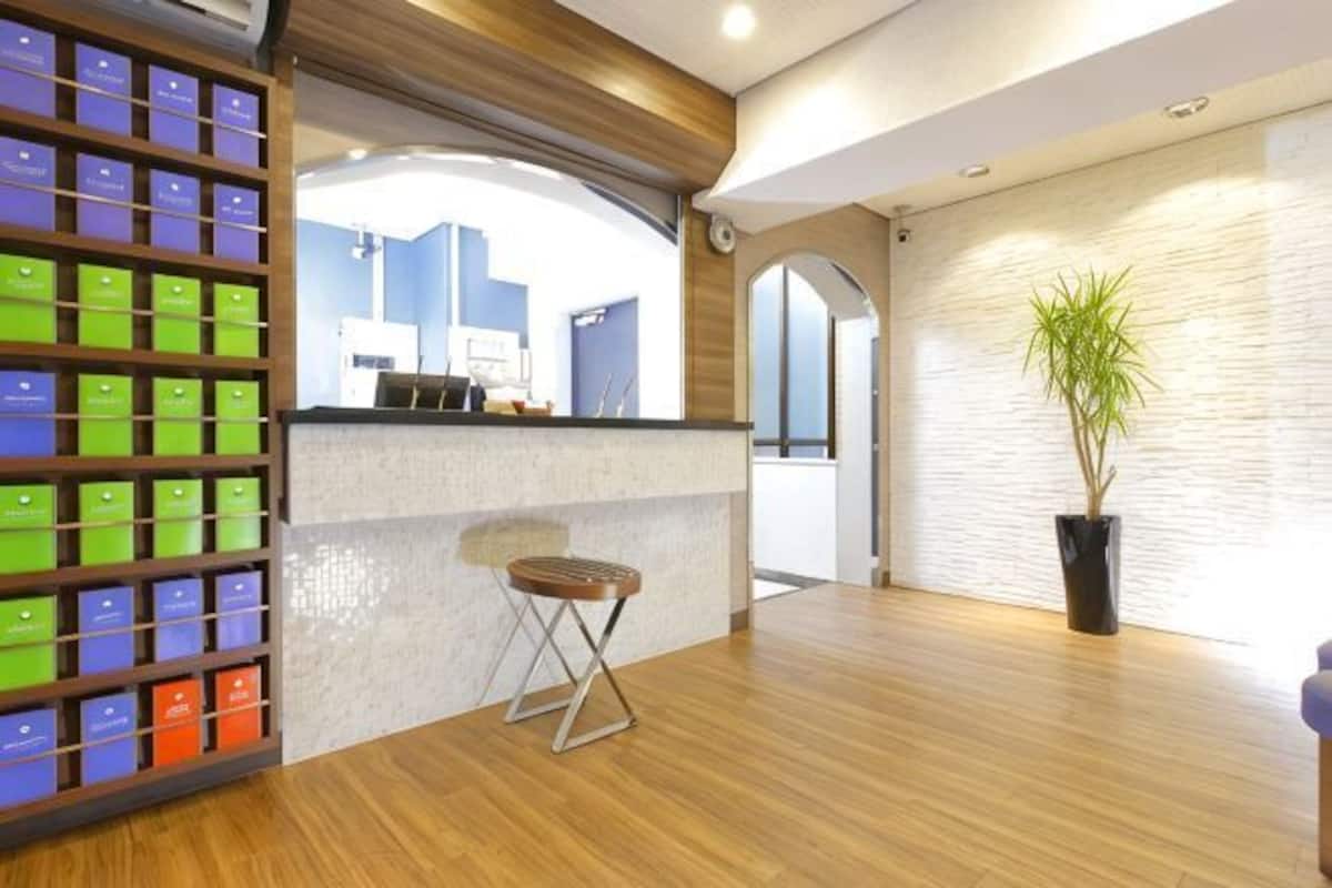 Un espace dâaccueil dotĂ© dâun plancher en bois, dâun comptoir de rĂ©ception, dâune plante et dâun mur au motif texturĂ©.