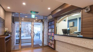 A reception area with a wooden counter, a glass door entrance, and a tiled wall. - Hotel MyStays Ueno Inaricho (Tokyo)