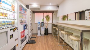 A modern bar area with a vending machine, a plant, and bar stools. - Hotel MyStays Ueno Inaricho (Tokyo)