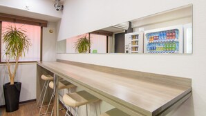 A bar area with a long counter, bar stools, and a refrigerator stocked with beverages. - Hotel MyStays Ueno Inaricho (Tokyo)