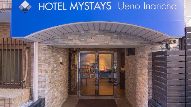 The entrance of HOTEL MYSTAYS Ueno Inaricho with a stone facade and a glass door leading inside. - Hotel MyStays Ueno Inaricho (Tokyo)
