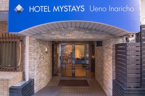 La entrada del HOTEL MYSTAYS Ueno Inaricho, con fachada de piedra y puerta de cristal que da al interior.