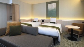 Een hotelkamer met twee bedden, een bank, een kleine tafel en een kast.