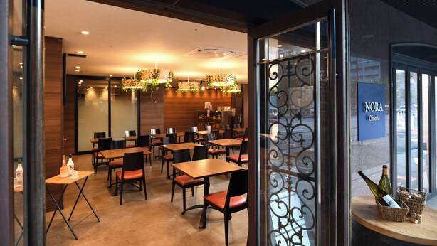 A restaurant interior with tables and chairs, a chandelier, and a sign reading 'Osteria NORA.' - Hotel MyStays Ochanomizu Conference Center (Tokyo)