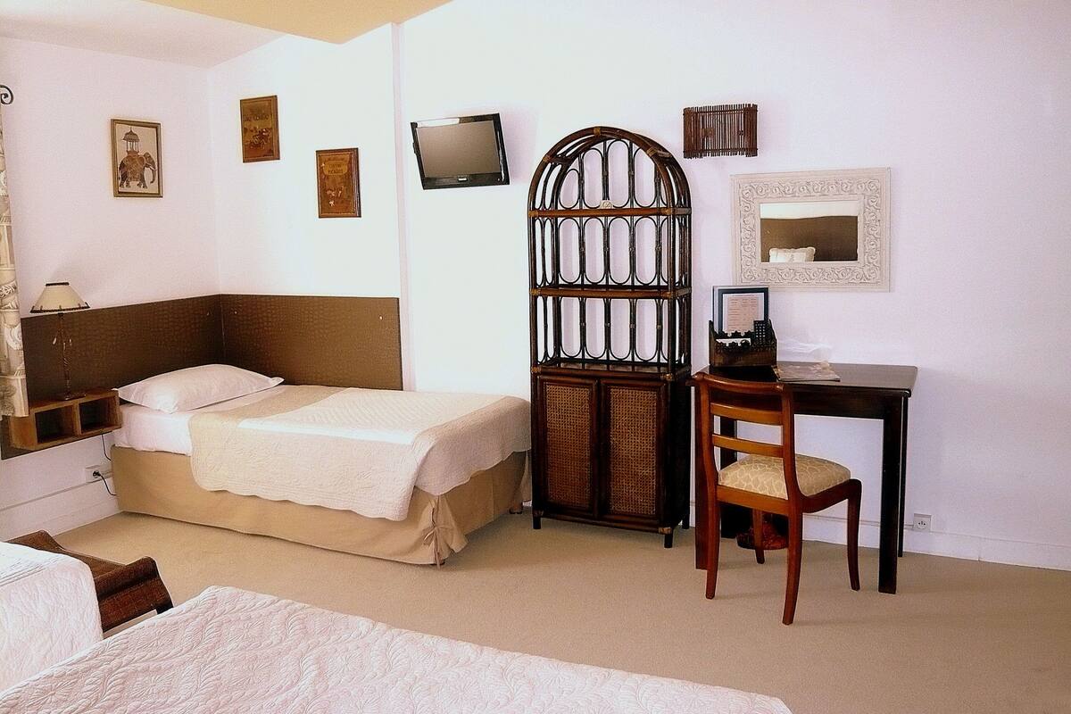 Une chambre d’hôtel comprenant un lit, un bureau, une chaise, un téléviseur et un paravent décoratif.