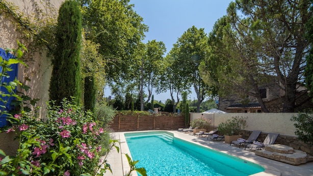 A swimming pool with lounge chairs and a stone wall.
