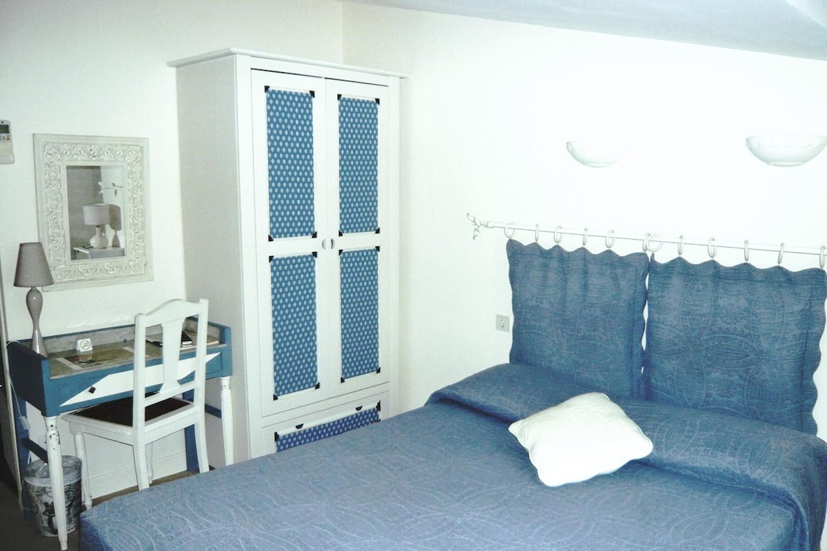 A bedroom with a bed, a desk, and a wardrobe.