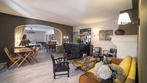A modern living room with a dining area, a fireplace, and a kitchen in the background.