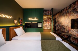 Habitación de hotel con dos camas, minibar, televisión y un letrero de neón.