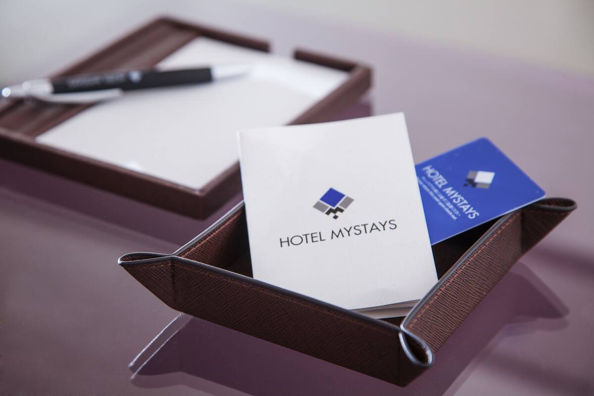 Ein braunes Lederbriefmappe mit einer weißen Karte mit der Aufschrift "HOTEL MYSTAYS" und einer blauen Karte mit dem gleichen Logo.
