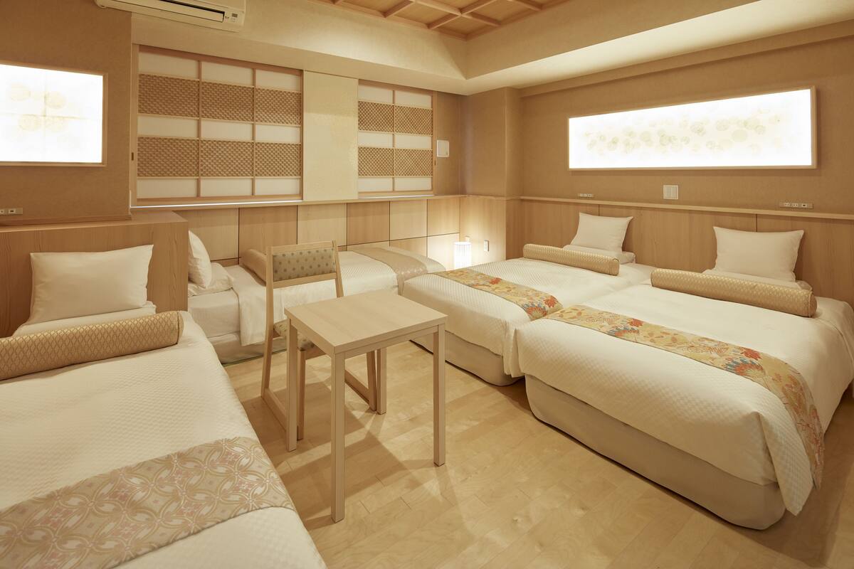 Ein Hotelzimmer mit zwei Betten, einem kleinen Tisch und einer traditionellen japanischen Schiebetür.