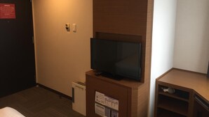 A hotel room with a television on a wooden stand, a small desk with a cup, and a trash bin. - Hotel MyStays Kamata (Tokyo)