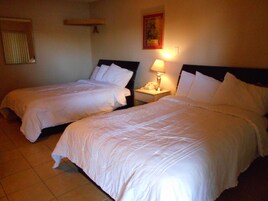 Två separata sängar med vita sängkläder i ett hotellrum.