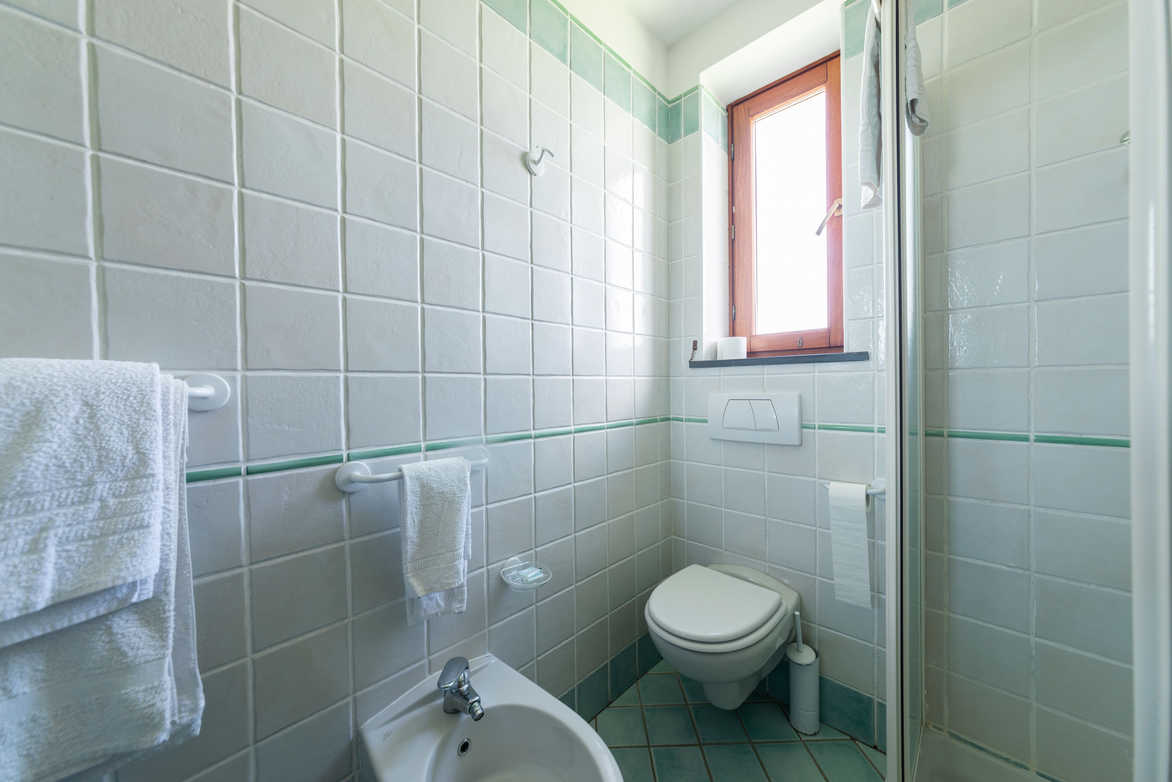 Ein kleines Badezimmer mit Toilette, Waschbecken und einem Fenster.