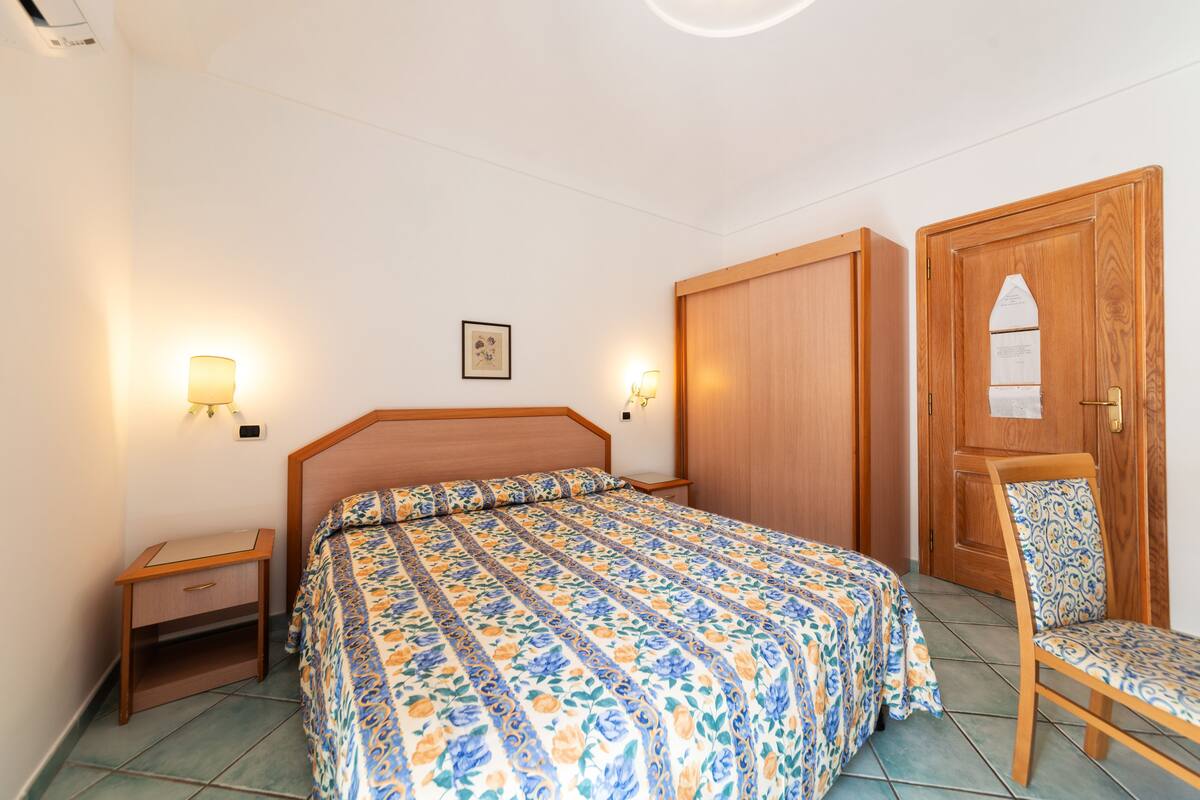 A bedroom with a large bed, bedside tables, a chair, and a wardrobe.