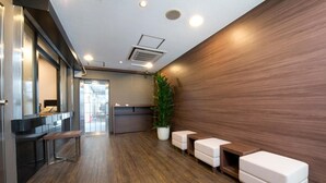 Un área de recepción moderna con piso de madera, mostrador de recepción, un banco y una planta en maceta.