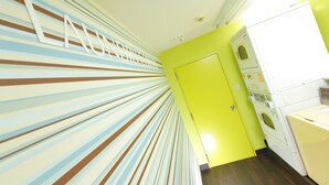 Un pasillo luminoso con paredes a rayas, una puerta y un área de lavandería con lavadoras.